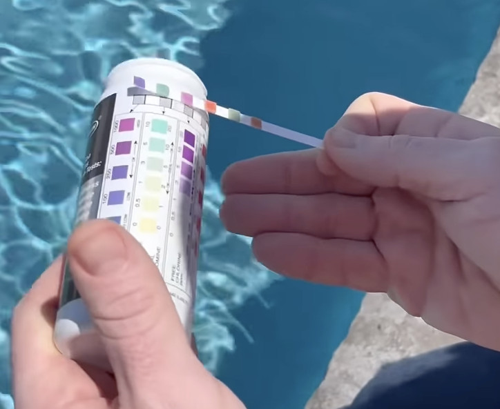 Comparing a pool test strip to the correct levels on a test strip bottle.